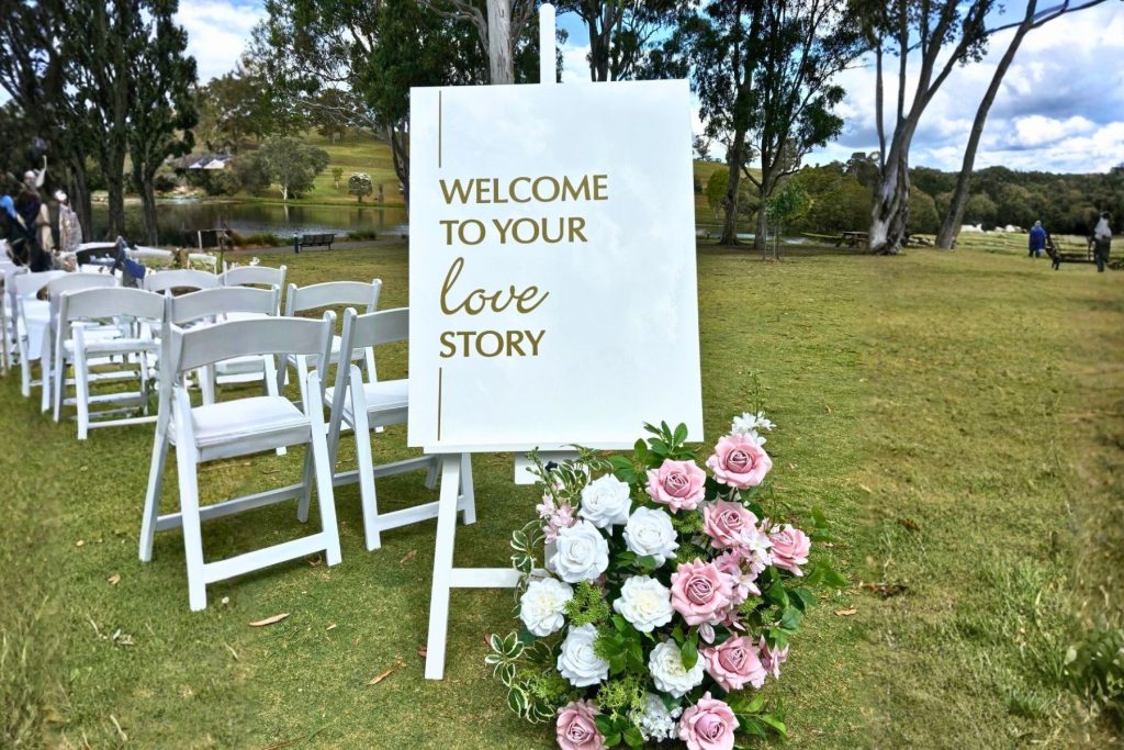 welcome signage with floral arrangements for wedding ceremony